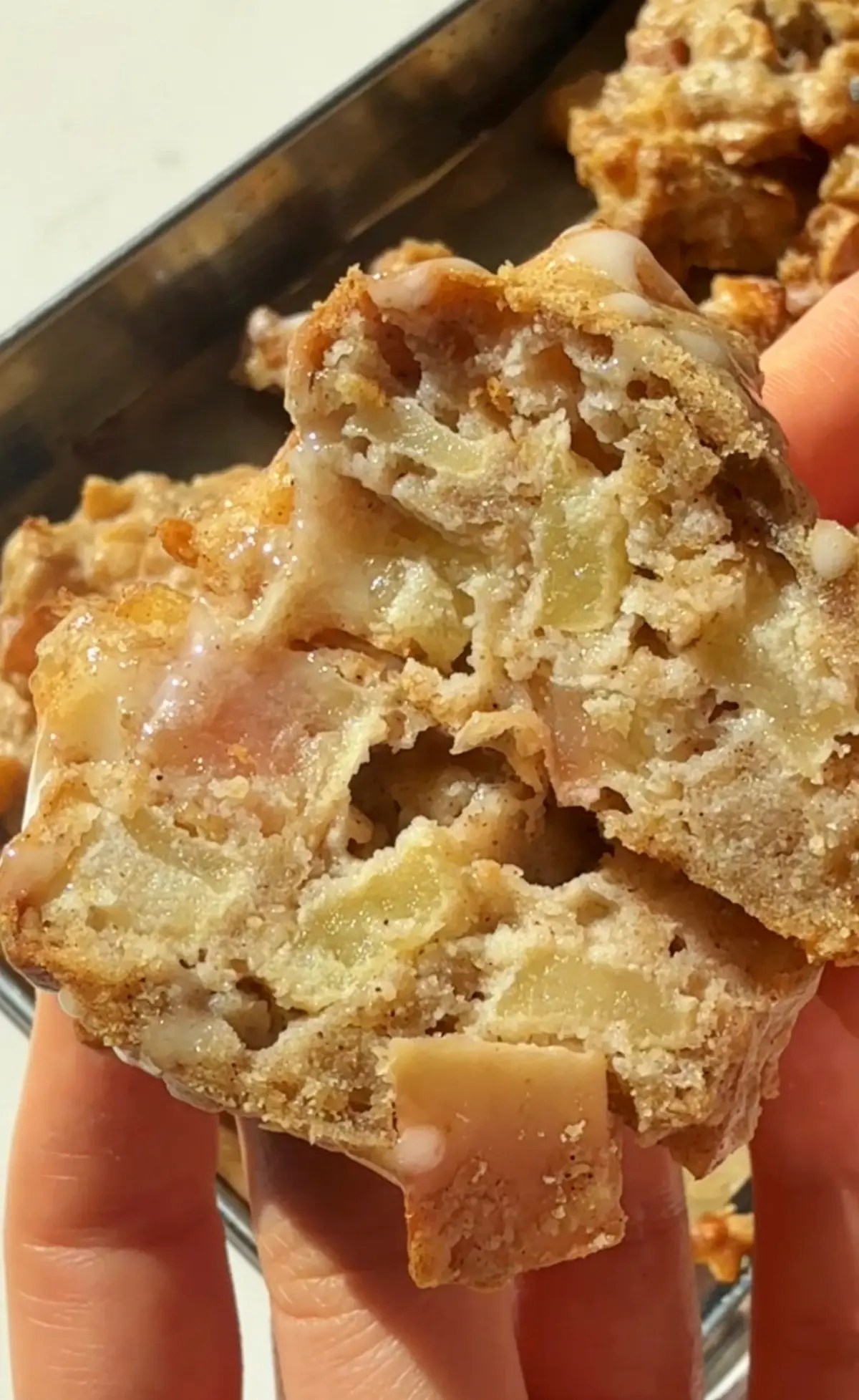 Apple fritter on a baking tray drizzled with icing