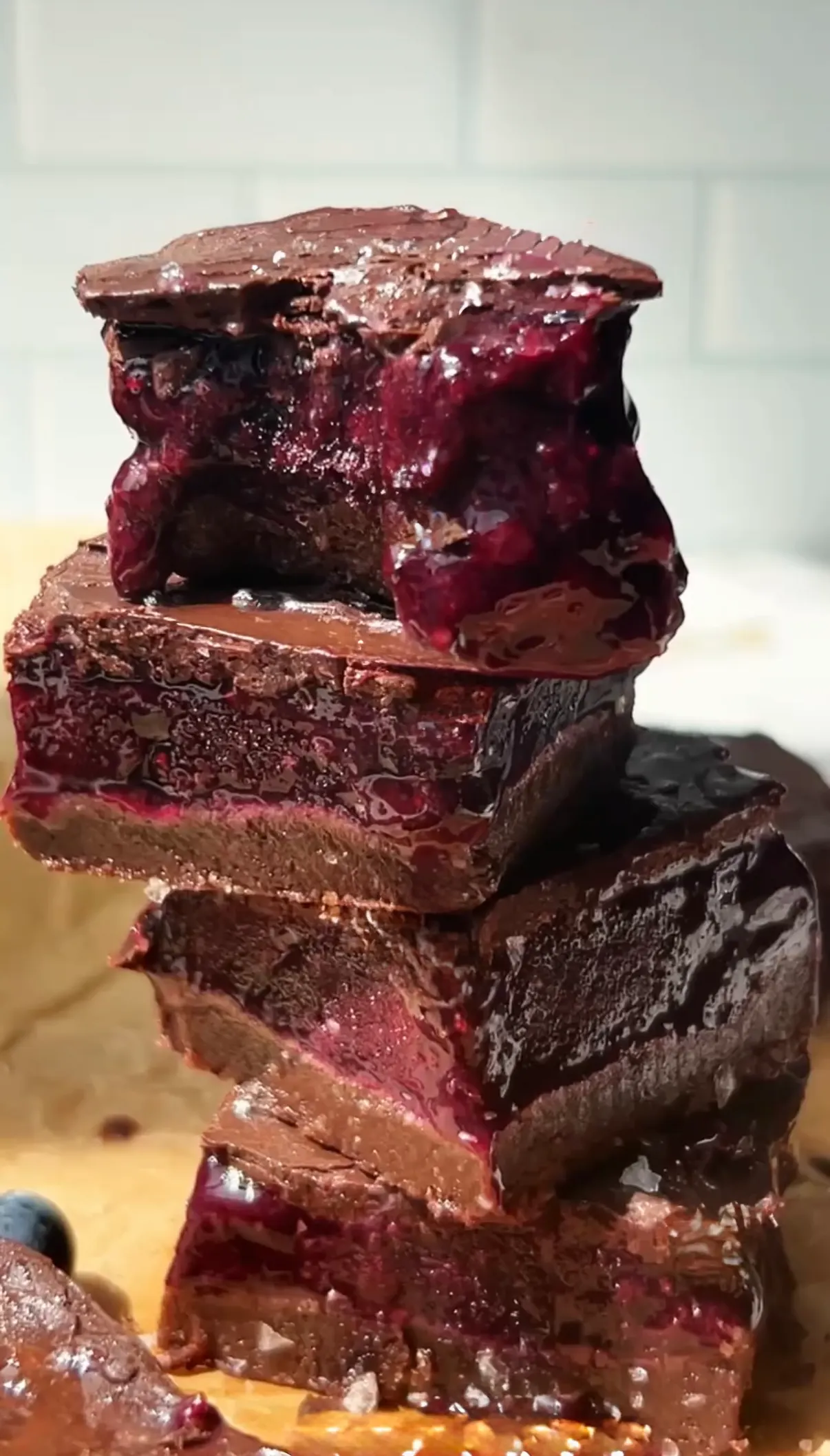 No bake blueberry chocolate bars sliced to show vibrant purple jam layer, chewy chocolate base and dark chocolate top