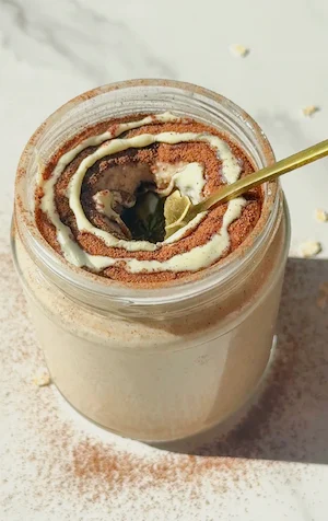 Blended cinnamon roll overnight oats in a jar with a gold spoon and cinnamon swirl topping