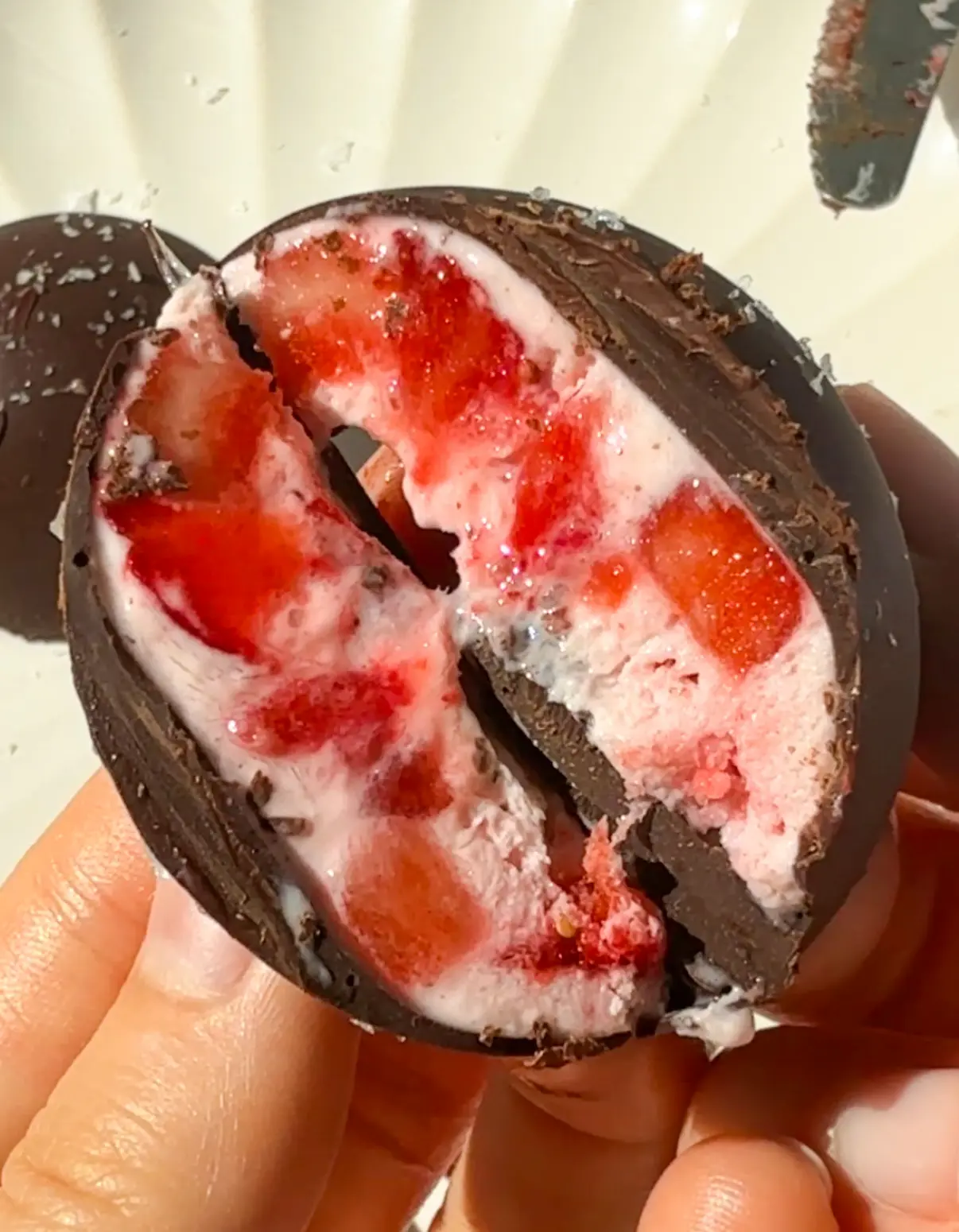 strawberries and cream bites - frozen strawberry greek yogurt coated in dark chocolate, cut open to show the pink filling