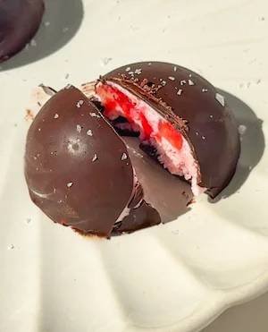 strawberries and cream bites coated in dark chocolate on a plate
